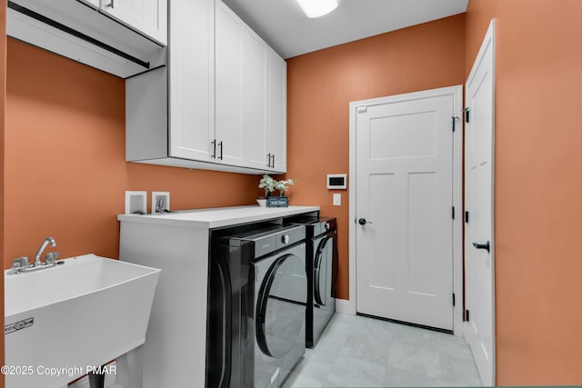 clothes washing area featuring cabinet space, a sink, and washing machine and clothes dryer