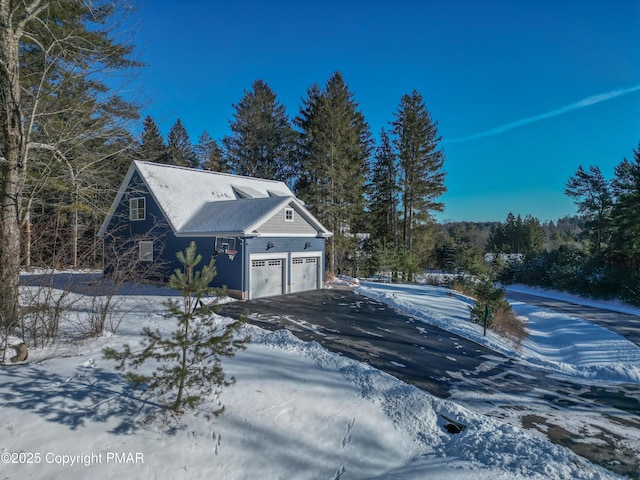 view of snow covered exterior featuring driveway and a garage