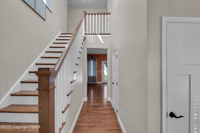 stairs featuring hardwood / wood-style flooring and a towering ceiling