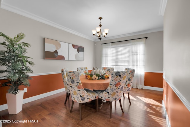 dining area featuring a chandelier, crown molding, baseboards, and wood finished floors