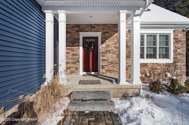 entrance to property featuring a porch and stone siding