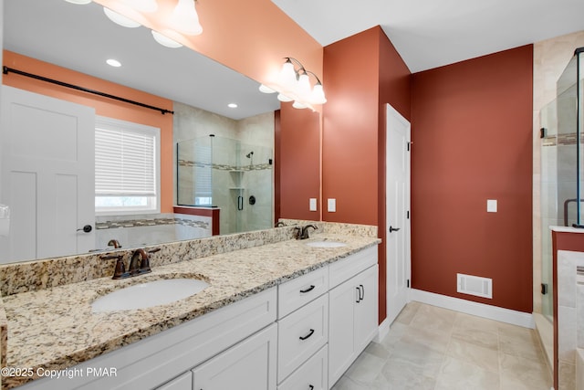 full bath featuring double vanity, a stall shower, visible vents, and a sink