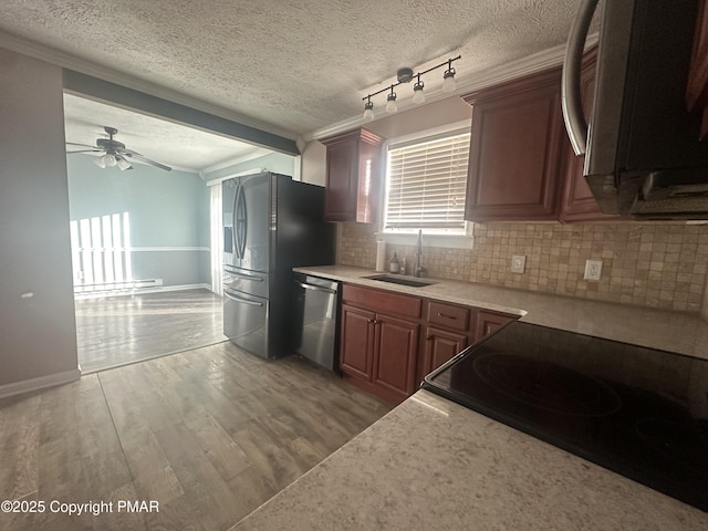 kitchen with sink, baseboard heating, backsplash, stainless steel appliances, and light hardwood / wood-style floors