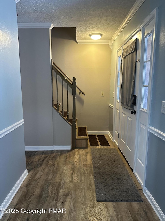 entrance foyer featuring crown molding, a textured ceiling, and dark hardwood / wood-style flooring