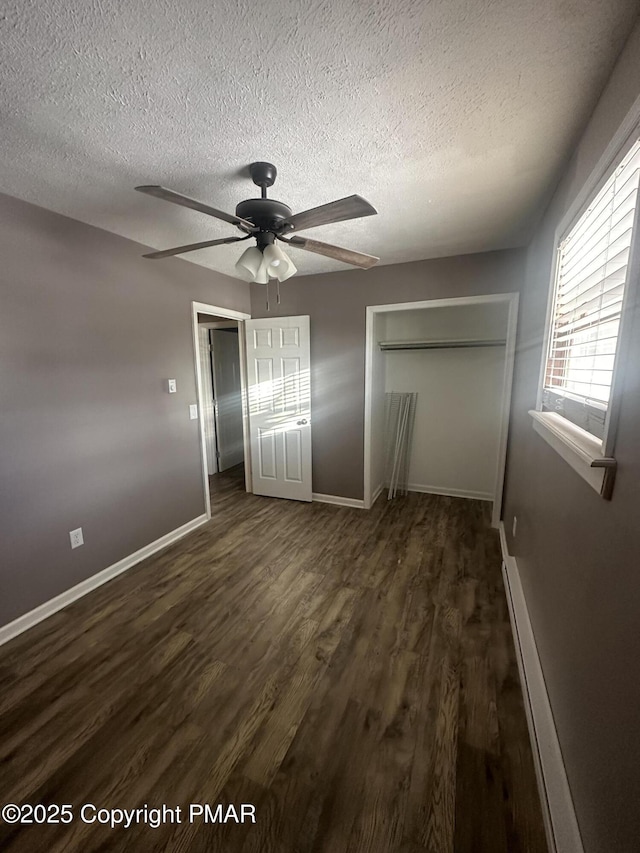 unfurnished bedroom featuring dark hardwood / wood-style floors, a baseboard heating unit, ceiling fan, a textured ceiling, and a closet