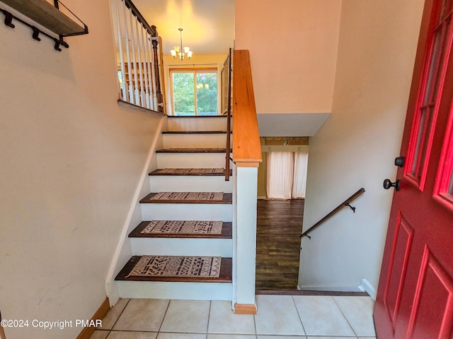 stairs featuring a notable chandelier, baseboards, and tile patterned floors