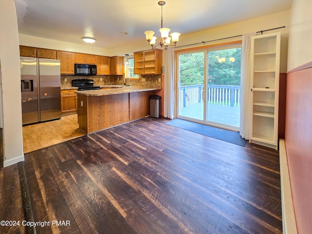 kitchen featuring tasteful backsplash, brown cabinets, wood finished floors, a peninsula, and black appliances