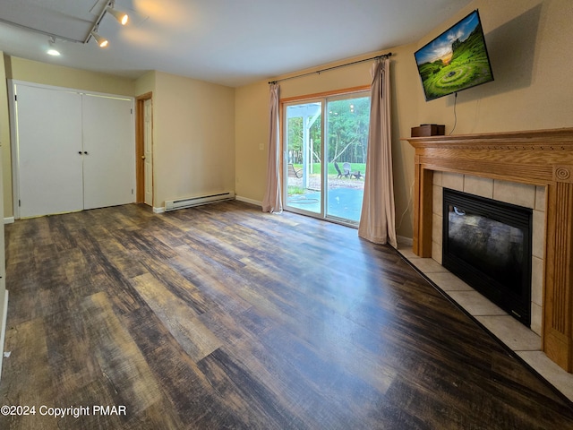 unfurnished living room featuring rail lighting, baseboard heating, wood finished floors, and a tile fireplace