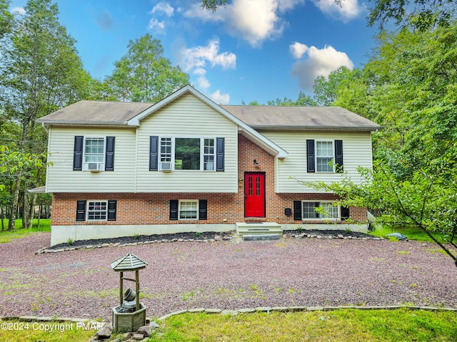 bi-level home featuring brick siding and cooling unit