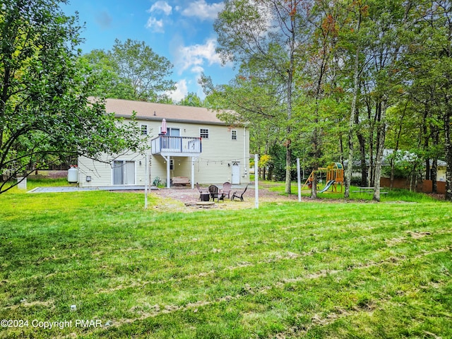 back of house featuring a fire pit, a lawn, and a playground