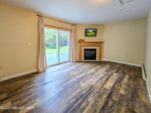 unfurnished living room with baseboards, a tiled fireplace, and wood finished floors