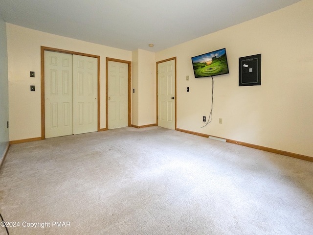 unfurnished bedroom with light carpet, electric panel, and baseboards