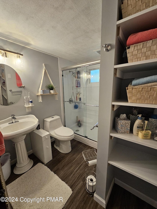 full bathroom with a stall shower, baseboards, toilet, wood finished floors, and a textured ceiling