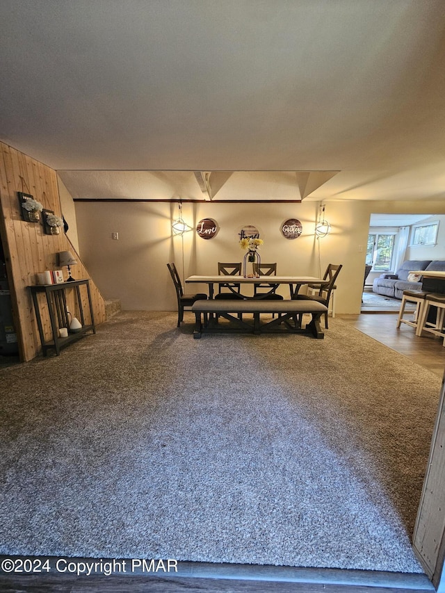 dining area featuring carpet and wooden walls