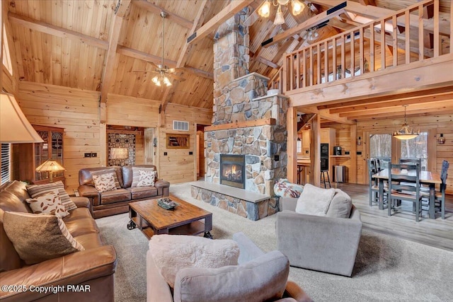 living room with ceiling fan, wooden ceiling, a stone fireplace, and wood walls