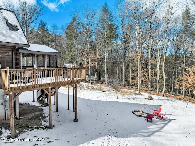 snowy yard featuring a forest view and a wooden deck