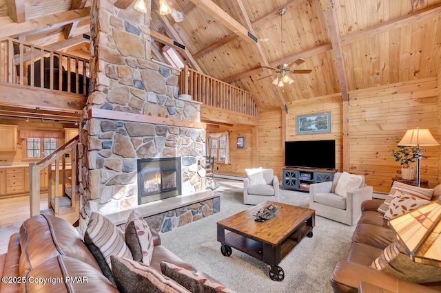 carpeted living area featuring a ceiling fan, wood ceiling, beamed ceiling, wood walls, and a fireplace