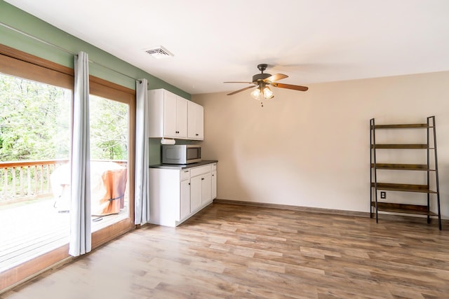 2227 Cheyenne Dr, Blakeslee, PA 18610 - kitchen with stainless steel microwave, white cabinets, ceiling fan, light wood-type flooring, and dark countertops