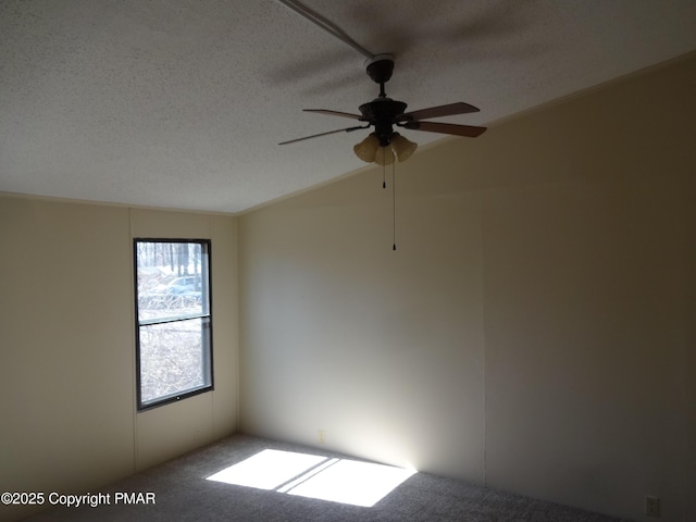 carpeted spare room featuring a ceiling fan, vaulted ceiling, and a textured ceiling