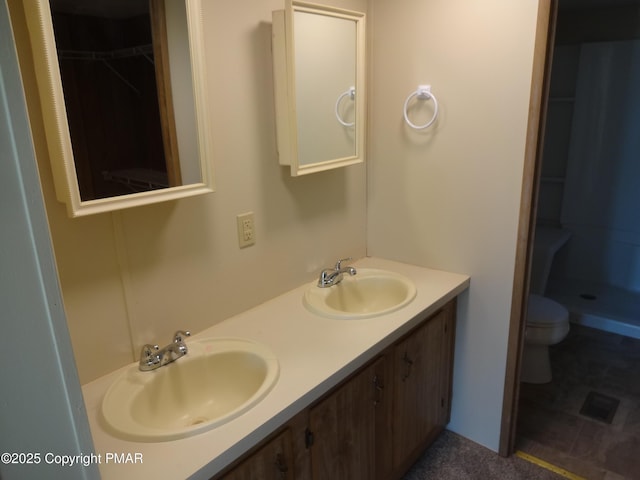 full bathroom featuring double vanity, a sink, toilet, and a walk in closet