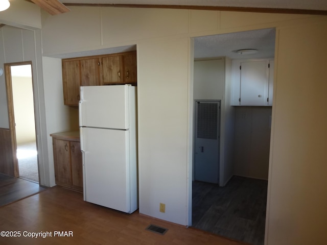 kitchen with visible vents, lofted ceiling, dark wood-style floors, freestanding refrigerator, and light countertops