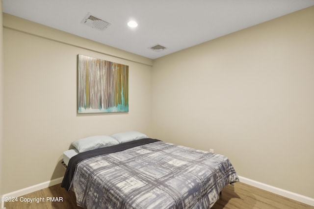 bedroom featuring baseboards, visible vents, and wood finished floors