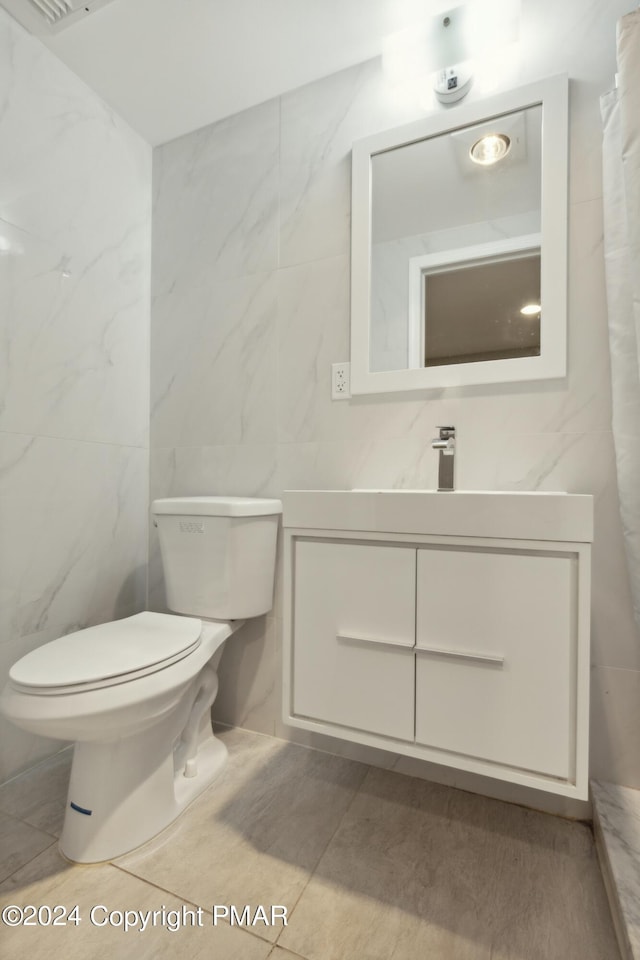 bathroom with toilet, tile walls, and vanity