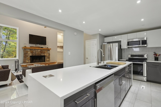 kitchen featuring stainless steel appliances, a sink, open floor plan, decorative backsplash, and an island with sink