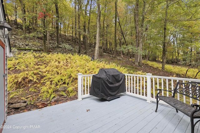 wooden deck featuring a forest view and area for grilling