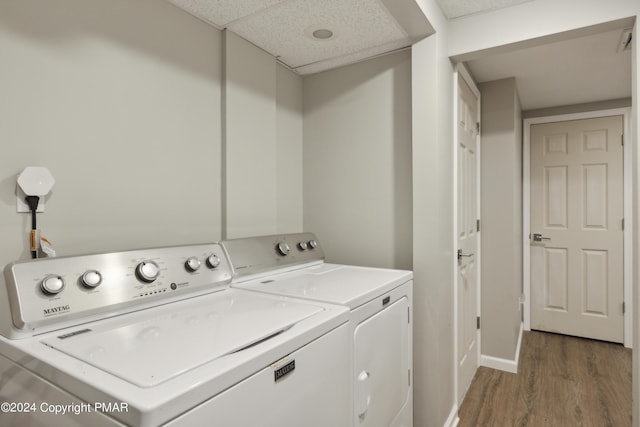 clothes washing area with laundry area, wood finished floors, washing machine and dryer, and baseboards