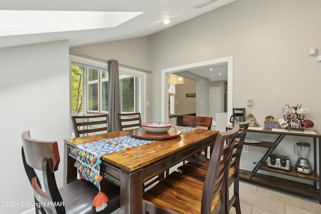 dining area with vaulted ceiling with skylight, visible vents, and light tile patterned flooring