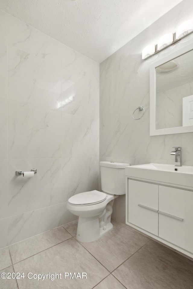 bathroom featuring toilet, a textured ceiling, tile walls, and vanity