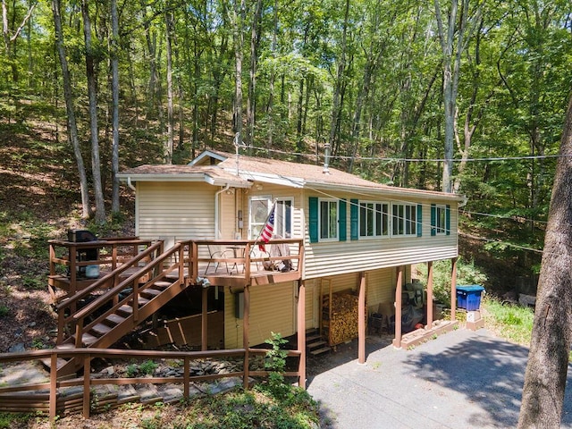 243 R Own Rd, East Stroudsburg, PA 18302 - view of front of house featuring a wooden deck, stairway, a view of trees, and asphalt driveway
