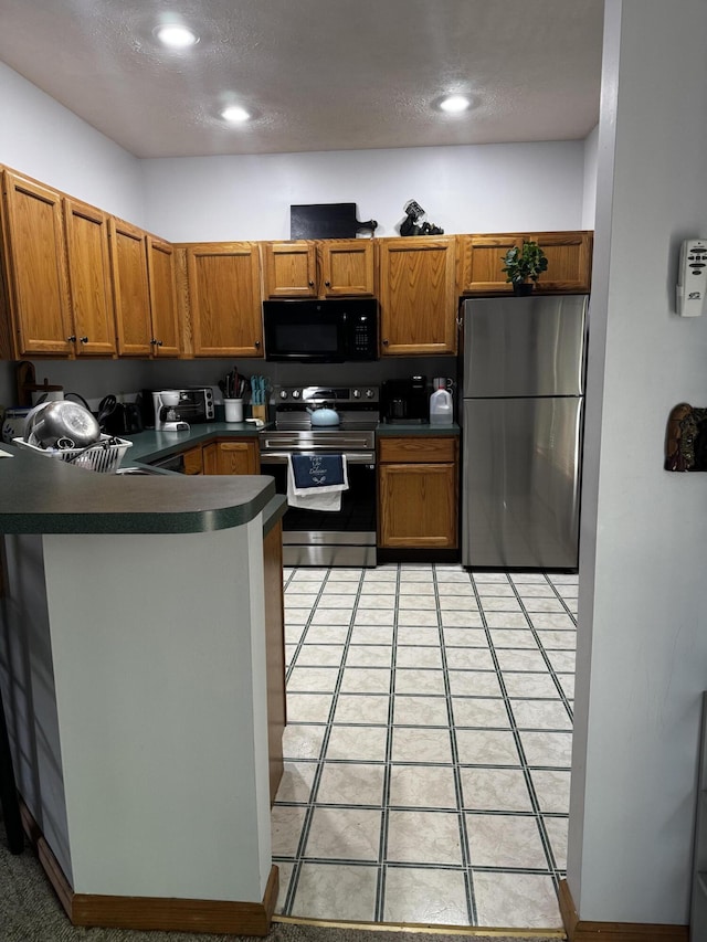 kitchen featuring appliances with stainless steel finishes, dark countertops, a peninsula, brown cabinetry, and recessed lighting