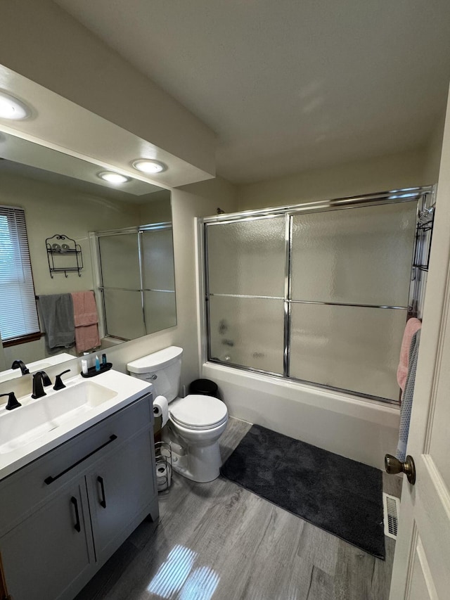 full bathroom featuring vanity, wood finished floors, and bath / shower combo with glass door