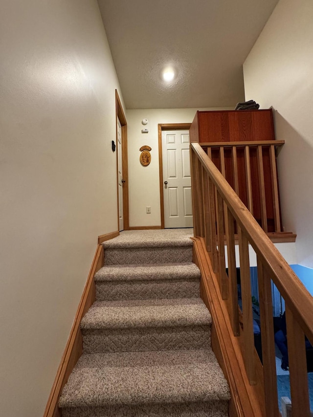 stairway featuring baseboards and carpet floors