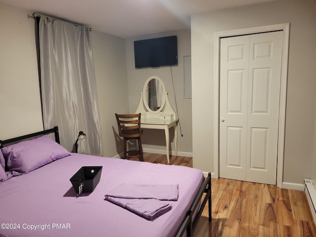 bedroom with light wood-style floors, a baseboard radiator, a closet, and baseboards