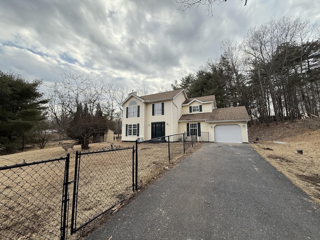 view of front of property featuring a garage, a gate, fence, and aphalt driveway