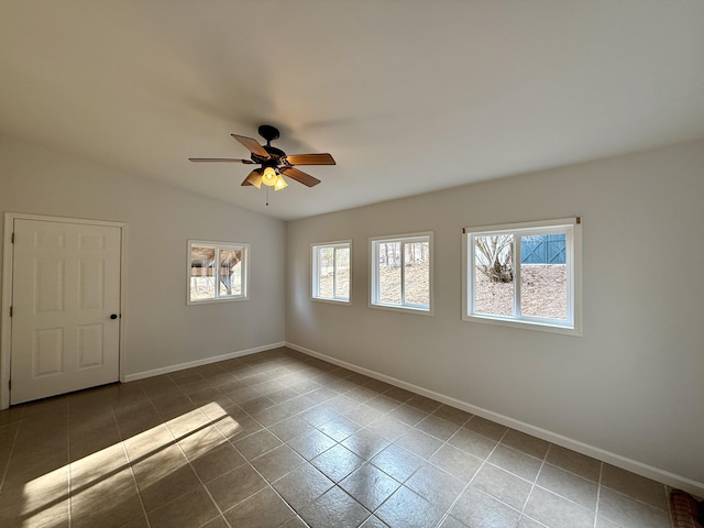 empty room with lofted ceiling, a ceiling fan, a wealth of natural light, and baseboards