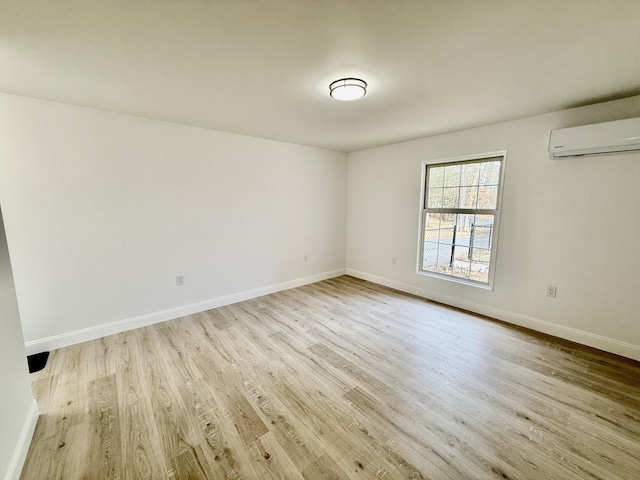 unfurnished room featuring a wall mounted air conditioner, baseboards, and wood finished floors