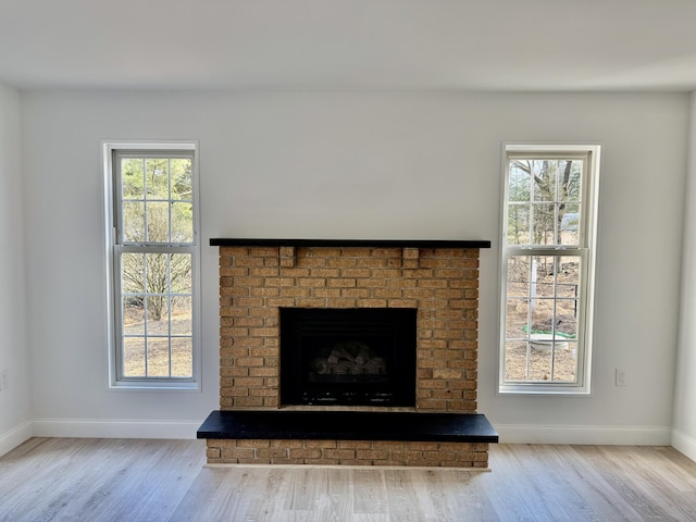 room details featuring a fireplace, baseboards, and wood finished floors