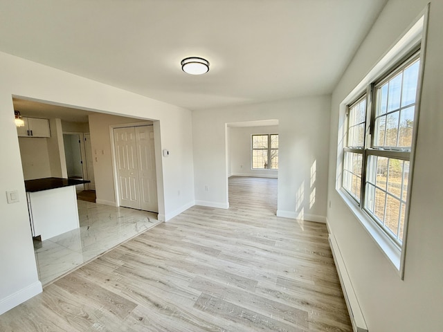 spare room with light wood finished floors, baseboards, and baseboard heating