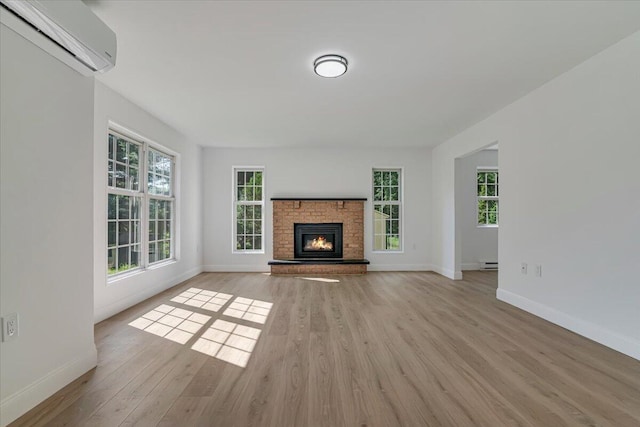 113 Dennis Ct, East Stroudsburg, PA 18301 - unfurnished living room with a wall mounted AC, light wood-style floors, healthy amount of natural light, and a brick fireplace