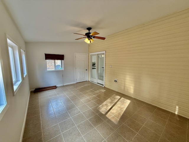 unfurnished room with ceiling fan, dark tile patterned floors, and baseboards