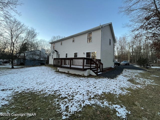 snow covered rear of property featuring a deck