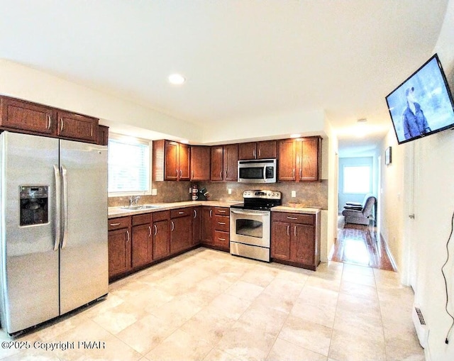 kitchen featuring stainless steel appliances, tasteful backsplash, a sink, and light countertops