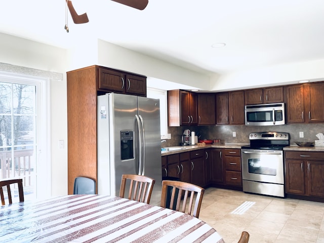 kitchen featuring stainless steel appliances, backsplash, ceiling fan, and light countertops