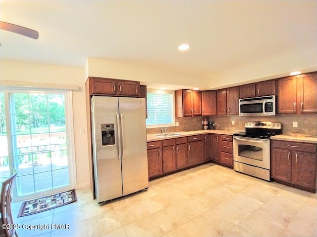 kitchen featuring a sink, stainless steel appliances, tasteful backsplash, and light countertops