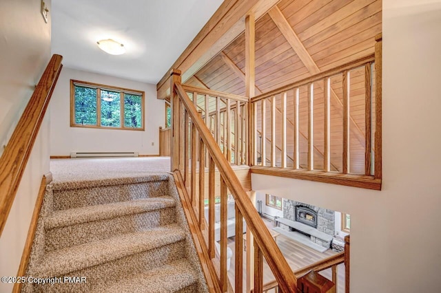 stairs with a baseboard radiator, beamed ceiling, and carpet flooring