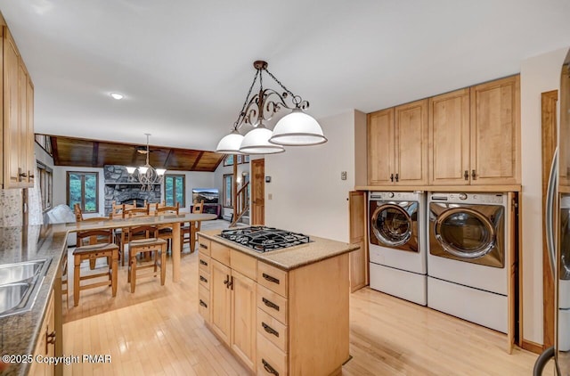 kitchen featuring hanging light fixtures, separate washer and dryer, light brown cabinetry, stainless steel gas stovetop, and light wood-type flooring